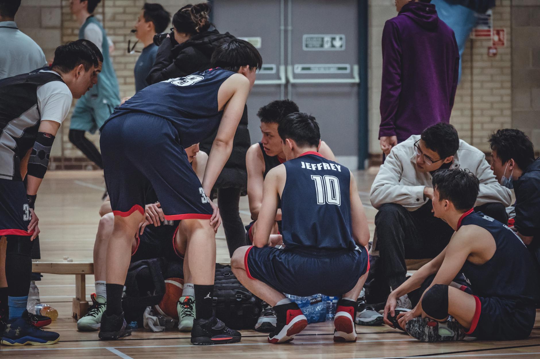 Basketball players discussing strategy during a break in a sports hall.