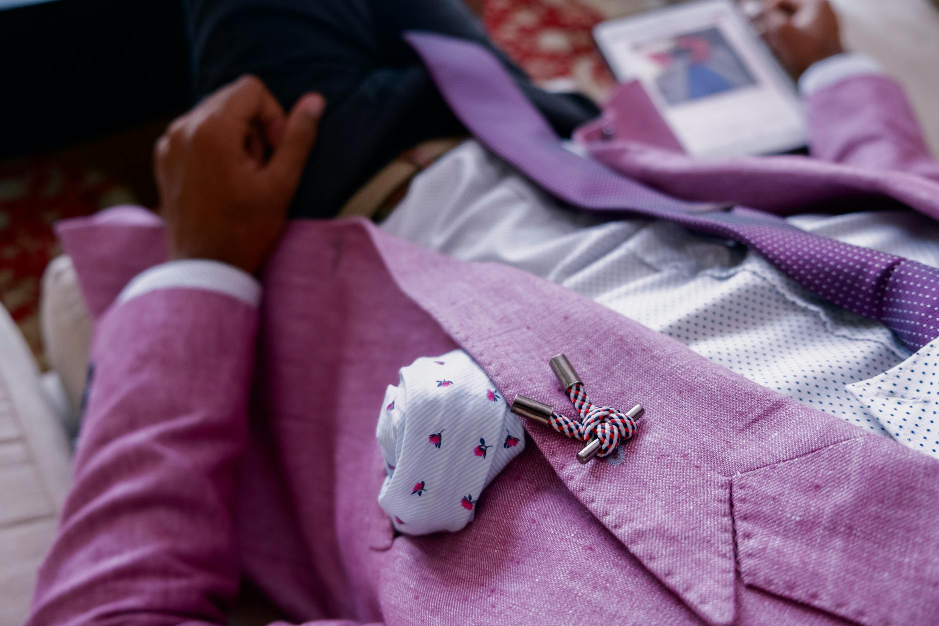Close-up of a stylish man in a pink suit and tie, showcasing modern fashion.