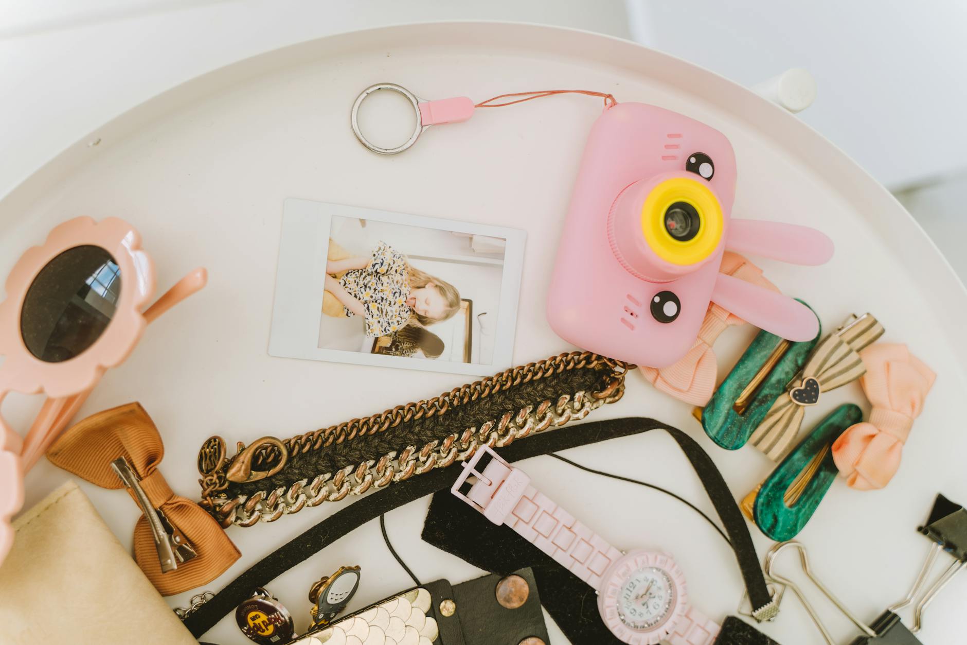 Flat lay of various accessories and a pink camera capturing vibrant style.