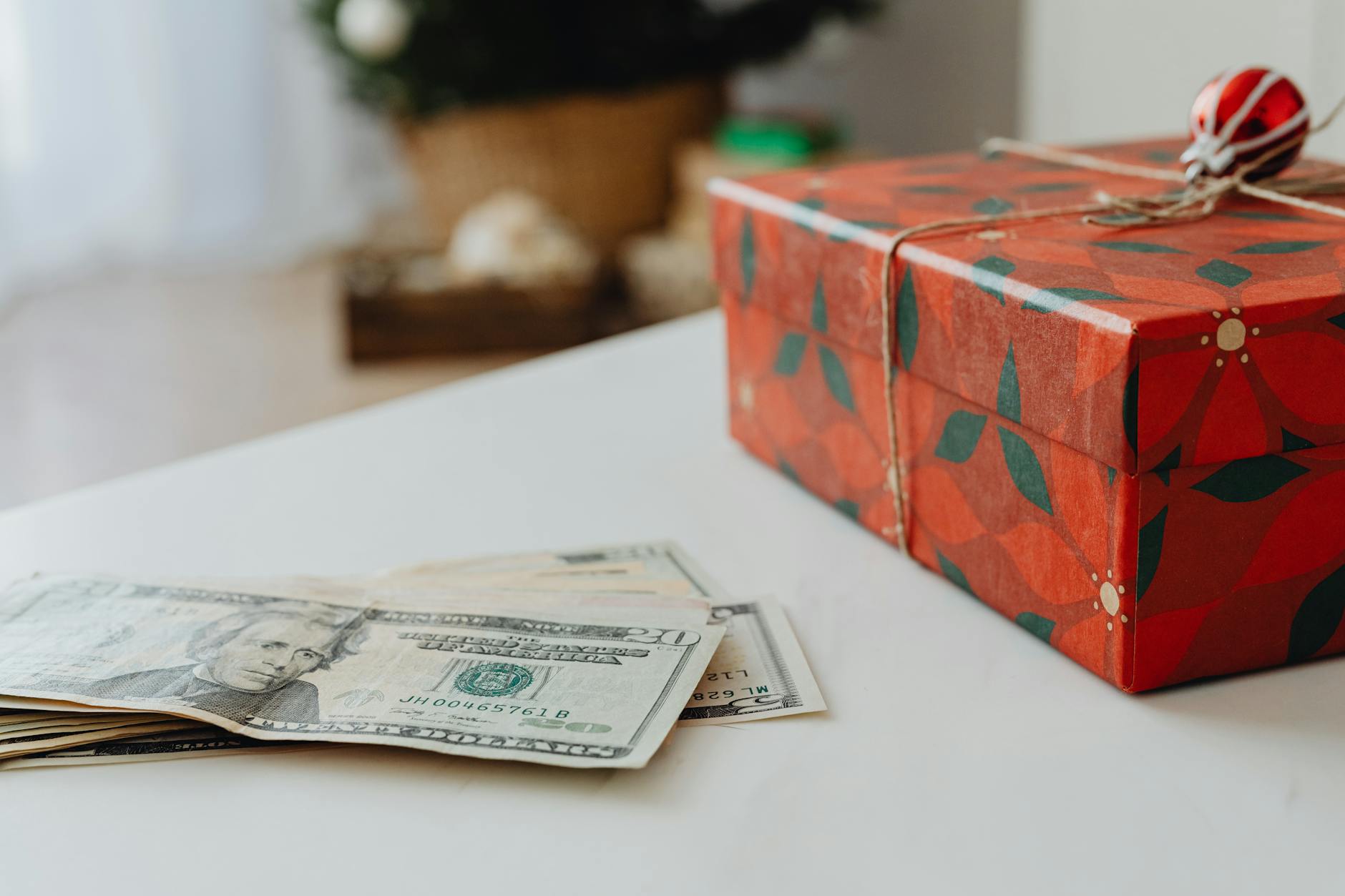 Red festive gift box with US dollar bills on a table, ideal for holiday-themed uses.