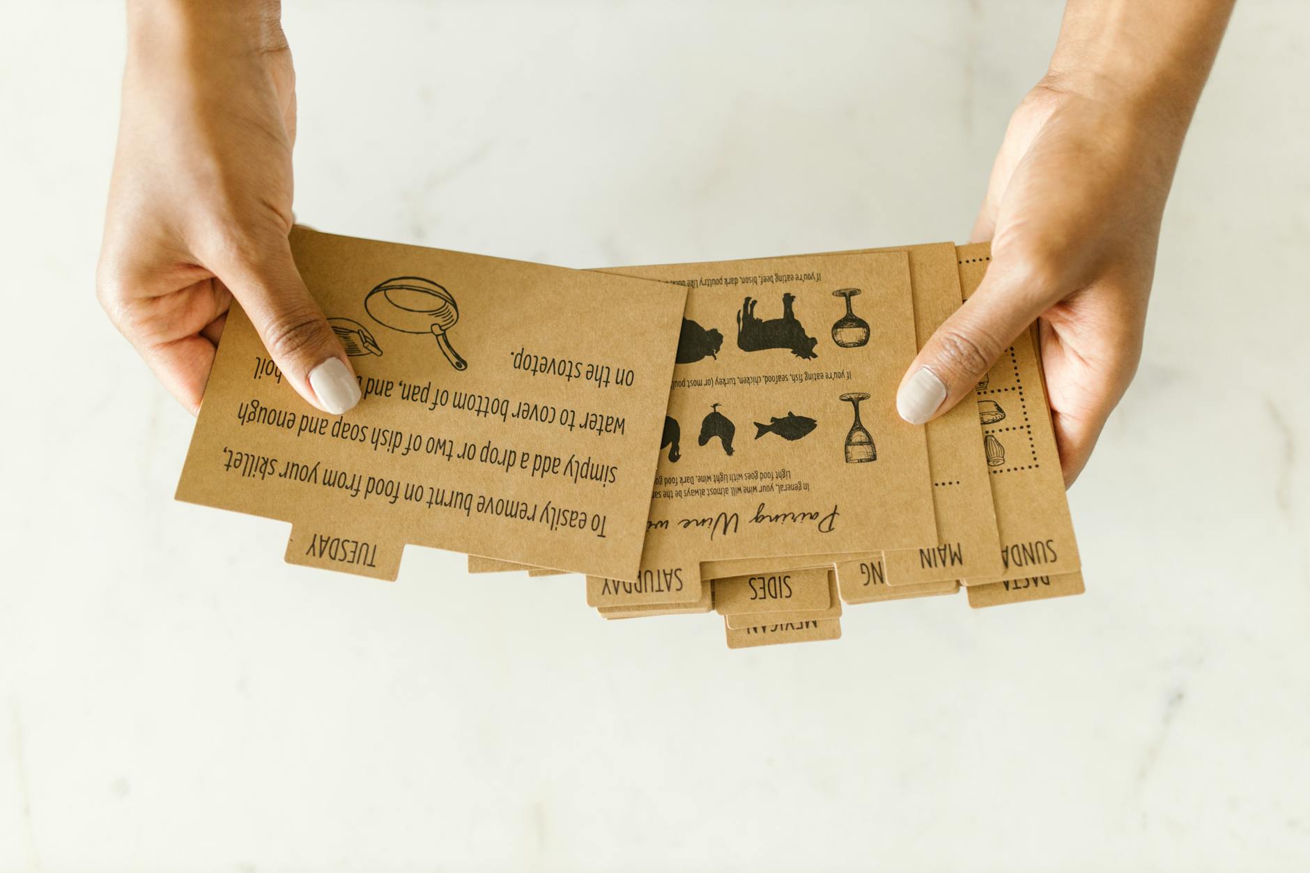 Brown kraft paper recipe cards held by hand on light background.
